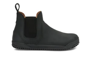 A black slip-on Chelsea Boot by Xero Shoes featuring elastic side panels, a pull tab at the back, rounded toe, and textured rubber sole. This simple design showcases visible stitching and a low heel—perfect for everyday styles.